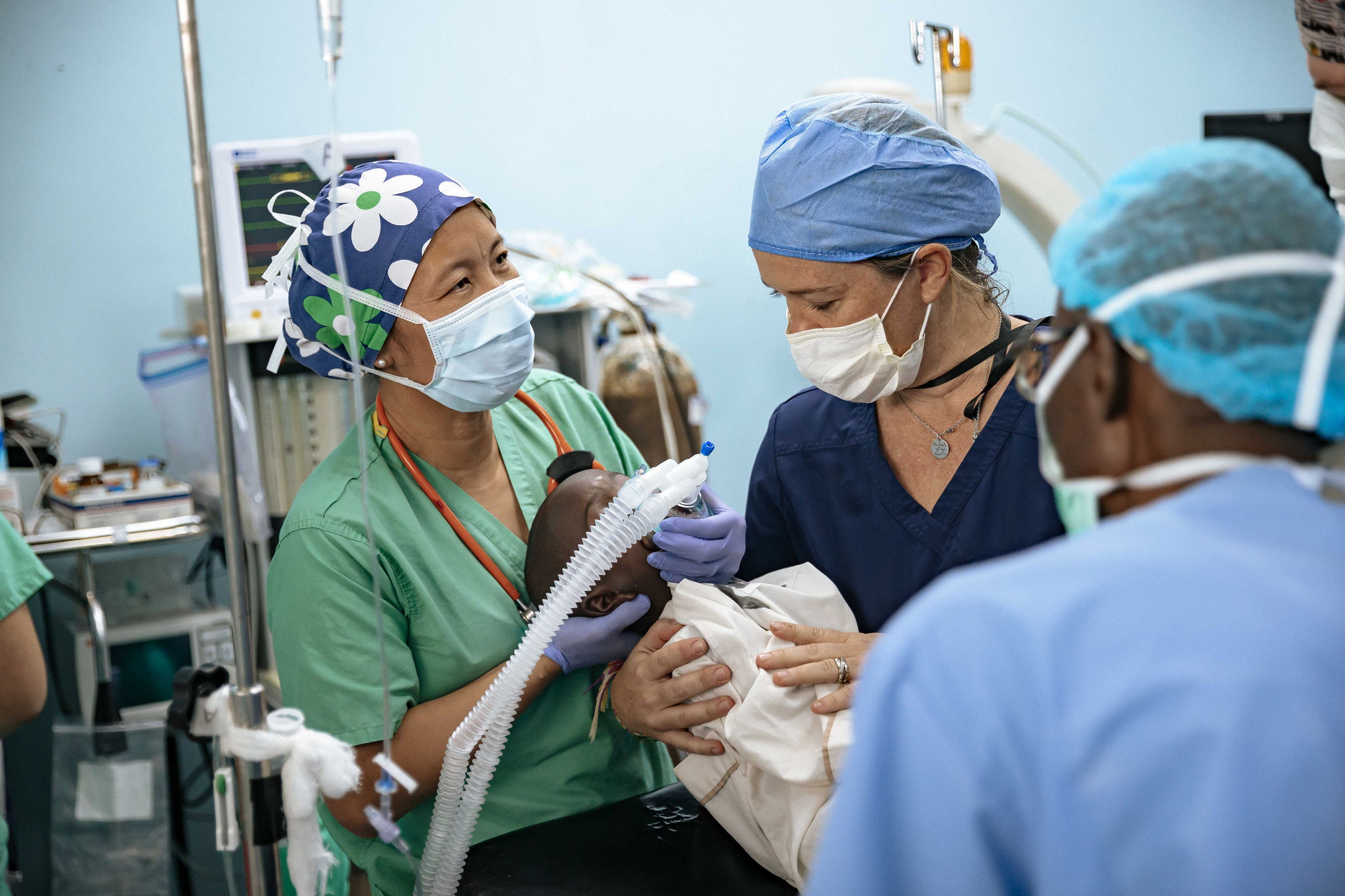 Surgeons holding a small child in an operating room