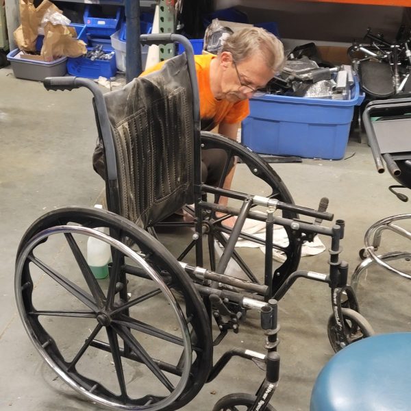 Volunteer fixing a wheelchair at our warehouse.